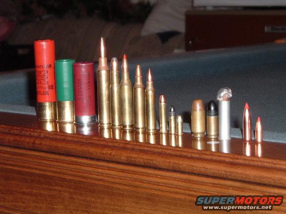 collection of various rifle and shotgun shells arranged on a wooden surface