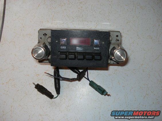 Car radio with knobs, buttons labeled CLOCK and RADIO, and a red digital display