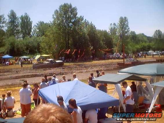 Brown 1976 Ford F-100 truck in mud, side view, with people and tents