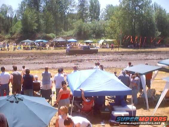 Muddy field with tents and people watching an event