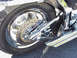 1999 Harley-Davidson Fat Boy - Close-up view of the rear wheel, brake system, and dual exhaust pipes on a motorcycle.