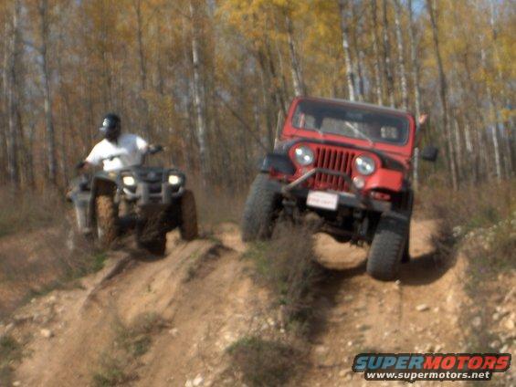 1979 Jeep CJ5 and ATV climbing a dirt hill, trees in background