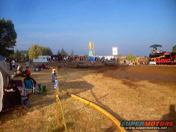 Mud bog event with spectators, a stage labeled Pirate Radio, and vehicles in the distance