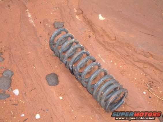 Coil spring lying on red, sandy ground