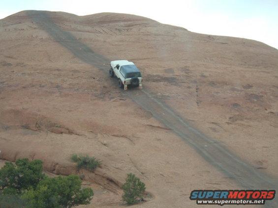 White 1993 Ford Bronco climbing a dirt road on a rocky hill