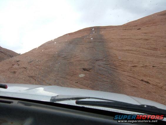Dashboard and windshield wipers in a vehicle looking up a steep, rocky hill