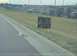 2003 Nissan 350Z - A cat lies by the roadside near a sign offering it for free, with a fenced parking lot in the background.