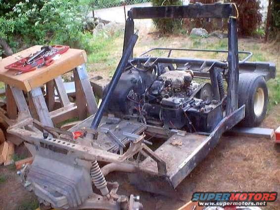 Go-kart chassis with engine and rear tire visible, tools on a stand nearby