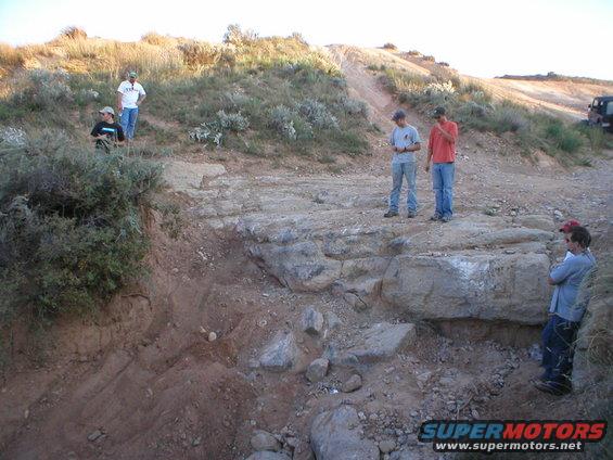 Off-road scene with people and a dark SUV in the distance