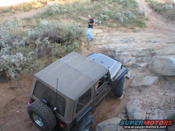 Brown Jeep Wrangler TJ navigating rocky terrain
