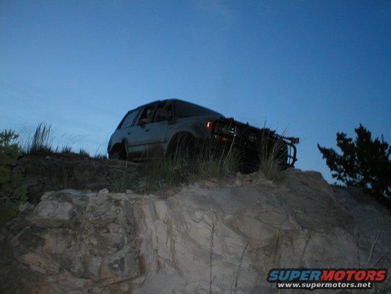 Gray SUV with a brush guard on a rocky incline under a clear blue sky