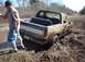 1978 Ford Bronco - A mud-covered pickup truck is stuck in a muddy field, with a person standing nearby.