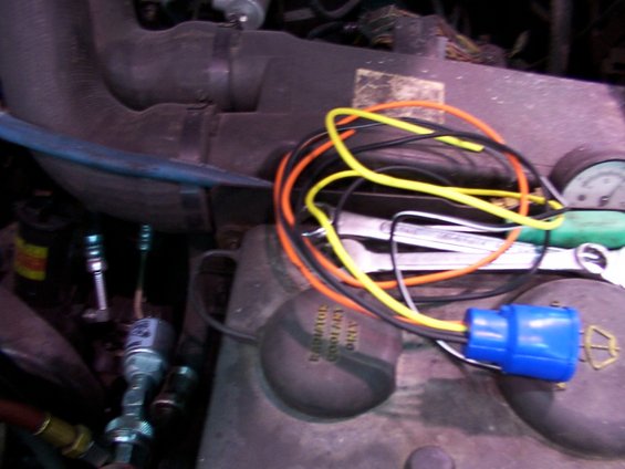 Engine bay with wires, a blue connector, and a radiator cap that says 'RADIATOR COOLANT ONLY'