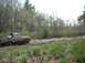 1978 Ford Bronco - A brown Ford Bronco navigates a muddy trail surrounded by trees.