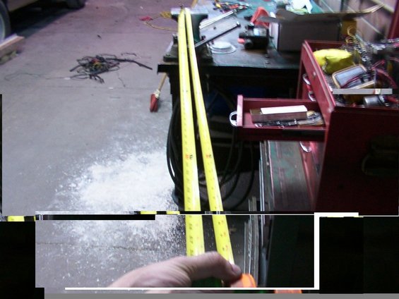 Two yellow tape measures are laid out on a concrete floor next to a red toolbox