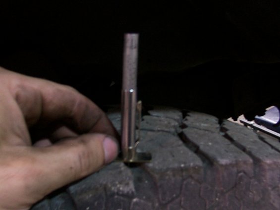Hand holding a tread depth gauge against a tire