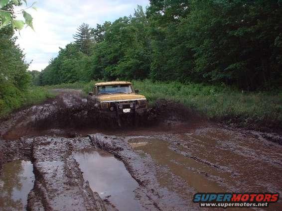 Yellow 1978 Ford Bronco driving through deep mud