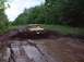 1978 Ford Bronco - A yellow 1978 Ford Bronco navigates a muddy trail, kicking up a large spray.