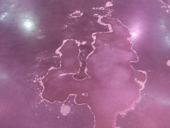 Close-up of peeling purple paint on a surface, showing damage and discoloration