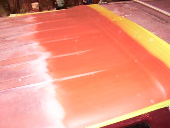 Vehicle roof section with red primer and yellow masking tape
