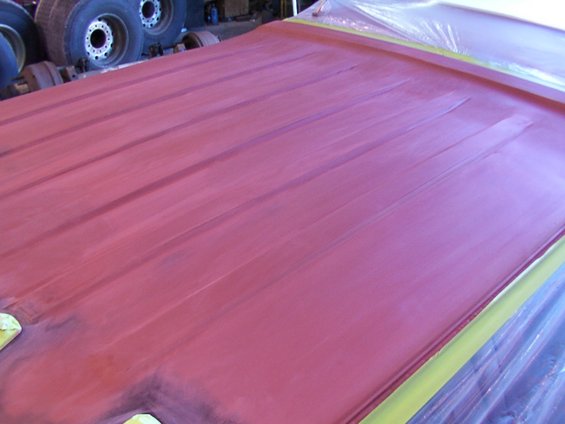 Red primer on ribbed truck roof, taped edges