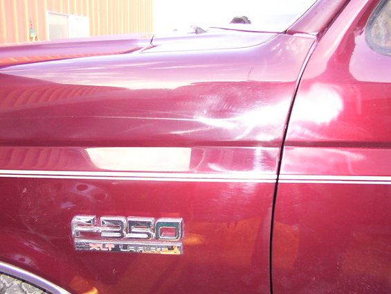 1988 Ford F-350 XLT Lariat badging on red fender and door with chrome trim