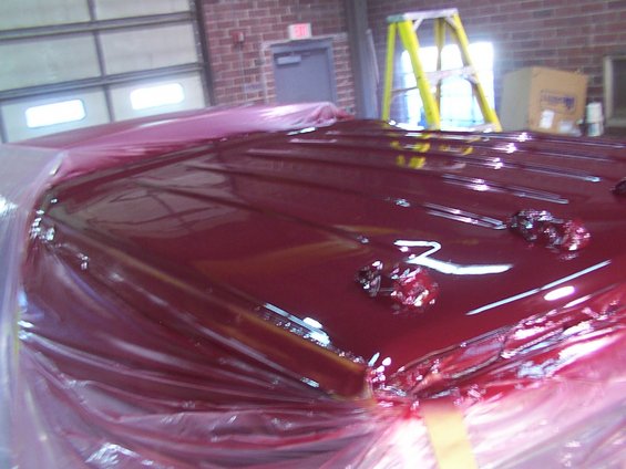 vehicle roof covered in red paint, wrapped in plastic