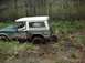 1978 Ford Bronco - A 1978 Ford Bronco is stuck in the mud off-road, with trees in the background.