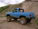 1989 Chevrolet Blazer - A lifted blue pickup truck is parked on a dirt road with a hilly background.