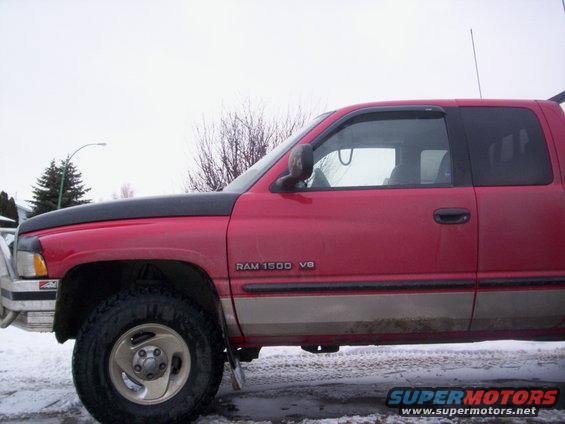 Red Dodge Ram 1500 V8 pickup truck side view, showing front fender, door, and rear cab