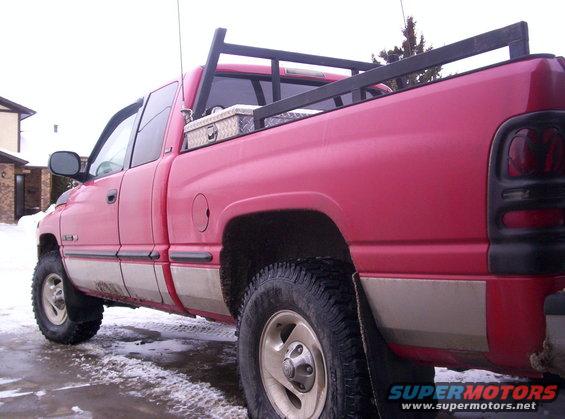 Red pickup truck with a toolbox in the bed and a rack over it. It has a two-tone paint job with tan lower panels