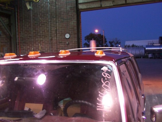 White writing on rear window of maroon vehicle reads "1989 05-09". Amber roof lights visible