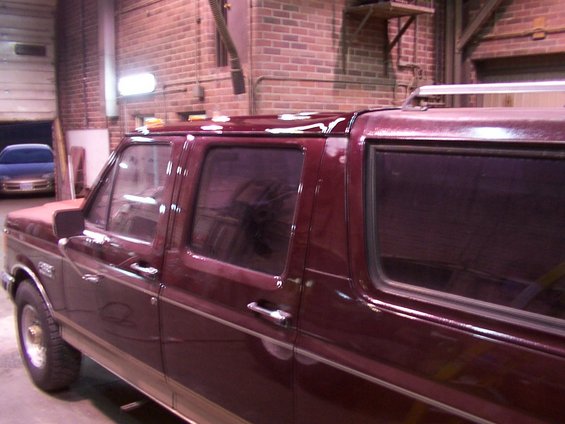 Maroon extended cab pickup truck with a custom roof extension, side view