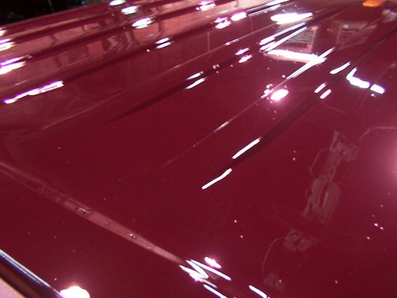 Maroon vehicle roof with reflections and visible panel lines