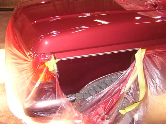 Red vehicle fender and hood detail covered in plastic wrap