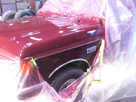 Red Ford F-250 truck fender and hood covered in plastic sheeting