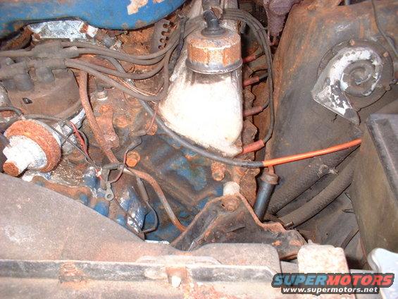 Rusty engine bay with blue engine block and orange spark plug wire