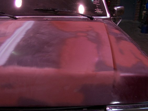 Red hood with primer patches and white sanding marks. Text on windshield