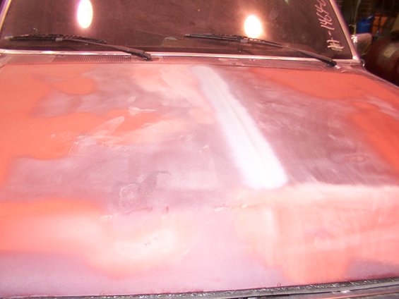 Hood of a vehicle undergoing bodywork, showing primer and filler. Windshield wipers visible