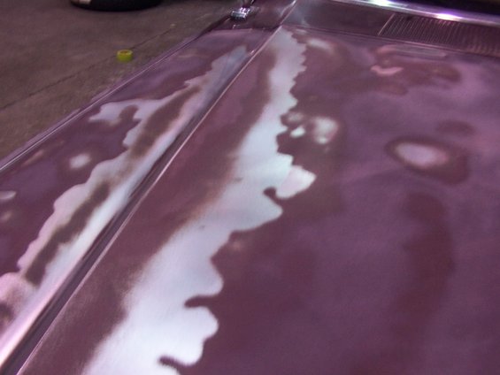 Purple vehicle hood with primer patches and paint damage