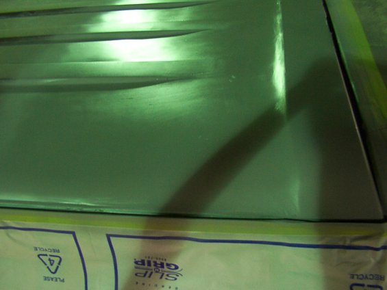 Green painted metal panel with horizontal ridges, covered in protective material