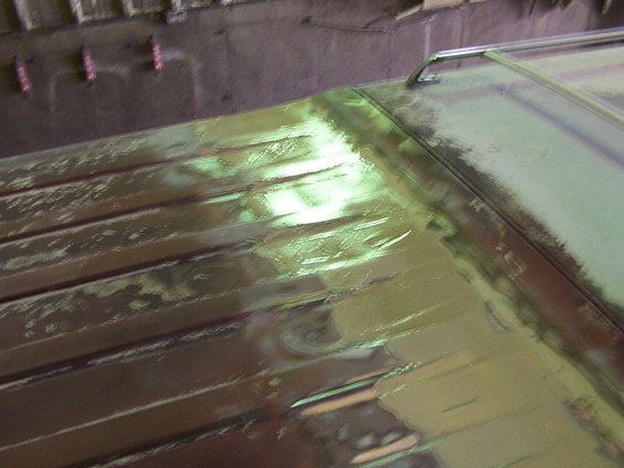 Close-up of a vehicle roof undergoing repair, showing body filler and primer
