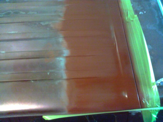 Orange roof panel section with masking tape, showing a transition from faded to freshly painted