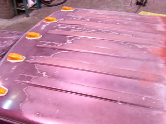 Close-up of a vehicle roof panel with multiple amber marker lights and visible paint damage