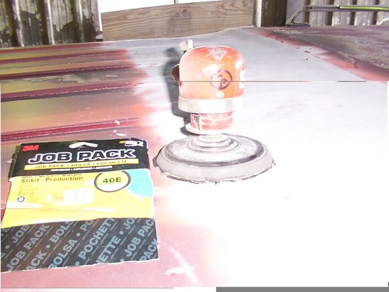 Orbital sander and 3M Job Pack sandpaper on a red vehicle roof with visible paint damage