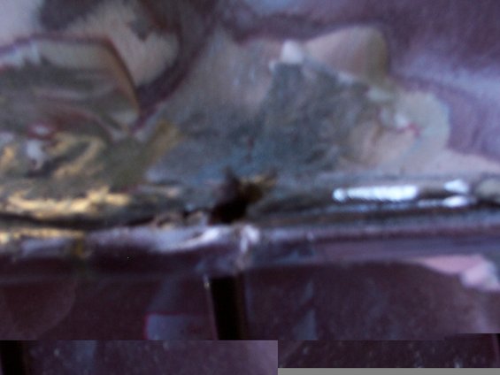 Close-up of damaged roof bodywork with peeling paint and exposed material