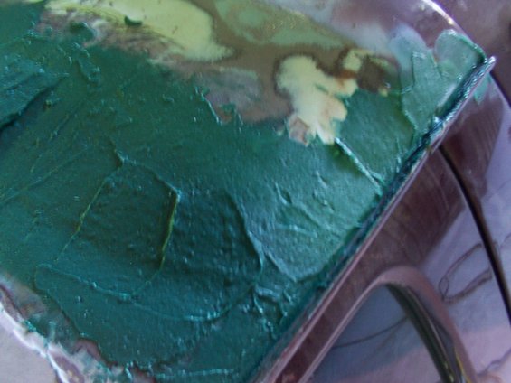 Car roof with green body filler and patches of primer, viewed from above