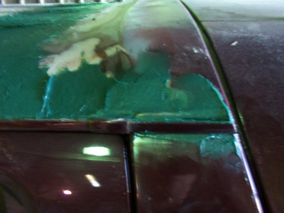 Car roof bodywork with green primer and paint damage