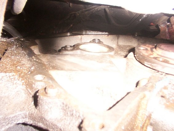 Close-up of a transmission bell housing with bolts and a gasket visible