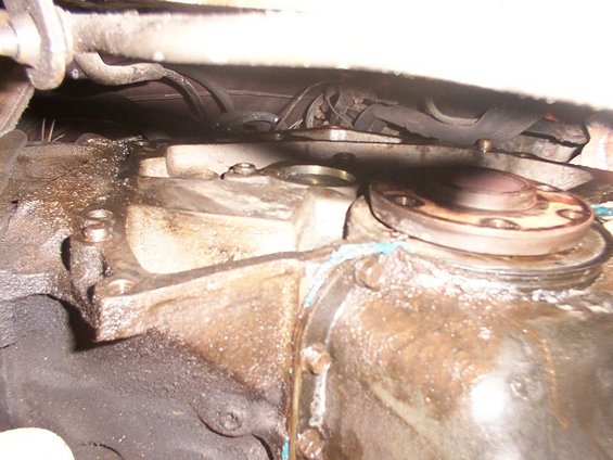 Close-up of a greasy transmission housing with bolts and a flange